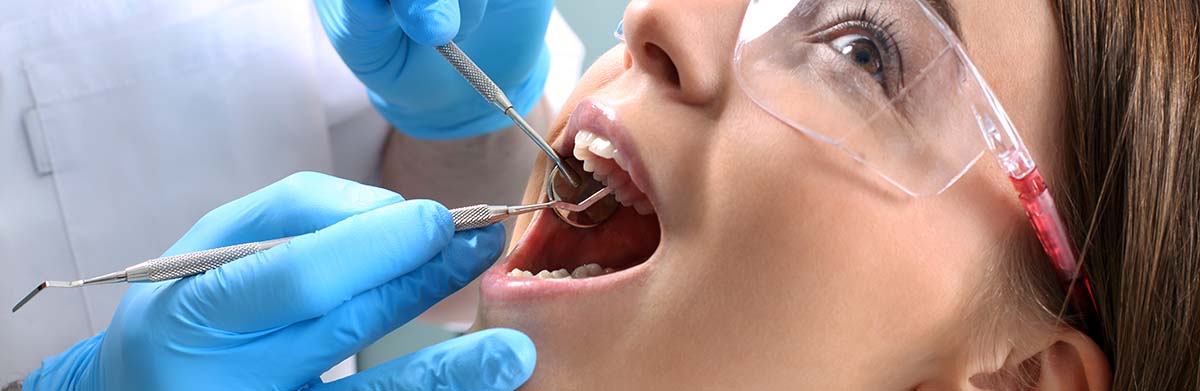 Dentist looking into spectacled Lady's mouth